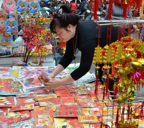 Khắp châu Á tưng bừng chuẩn bị đón Tết cổ truyền - 8 Một người phụ nữ bán bao lì xì và các đồ trang trí trên đường phố Hà Nội. (Ảnh: