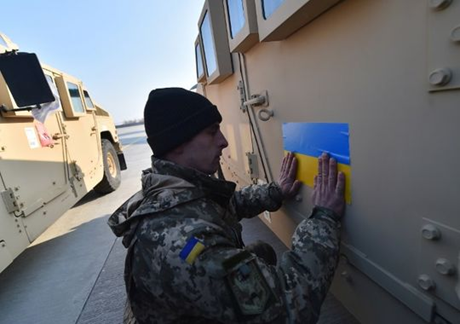 Một quân nhân Ukraine đang dán cờ nước này lên chiếc xe bọc thép mới nhận. (Ảnh: