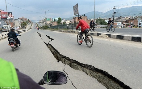 Một người đạp xe đi trên con đường nứt toác sau động đất. (Ảnh: 