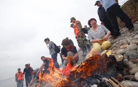 Người thân đốt tiền vàng cho các nạn nhân trên tàu Ngôi sao phương Đông. (Ảnh: