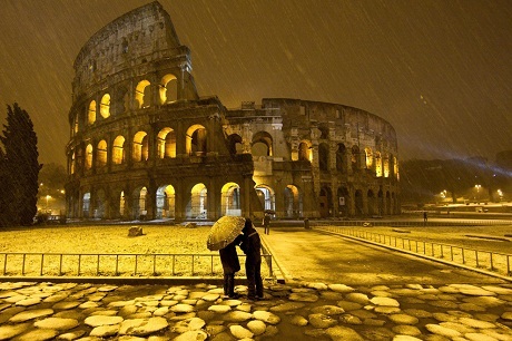 Hai thanh niên đứng trước đấu trường Colosseum dưới trời đổ tuyết ở thành phố Rome, Ý.