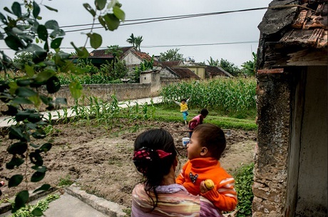 Bà Nhàn bế cháu đứng ngắm khu vườn nhỏ trước nhà