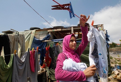 Một cô gái người Syria đang phơi đồ bên cạnh căn nhà lụp xụp ở thị trấn Alman, Lebanon.