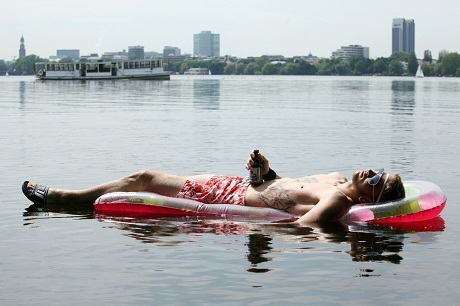Một người đàn ông nằm tắm nắng trên chiếc đệm hơi ở hồ Outer Alster, Hamburg, Đức.