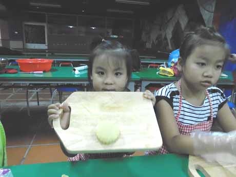 Một cô bé bẽn lẽn khoe chiếc bánh nướng đầu tay.