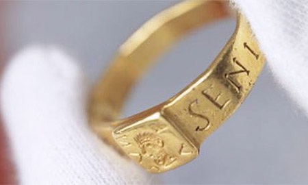Cận cảnh chiếc nhẫn vàng với dòng chữ Latin rõ nét.