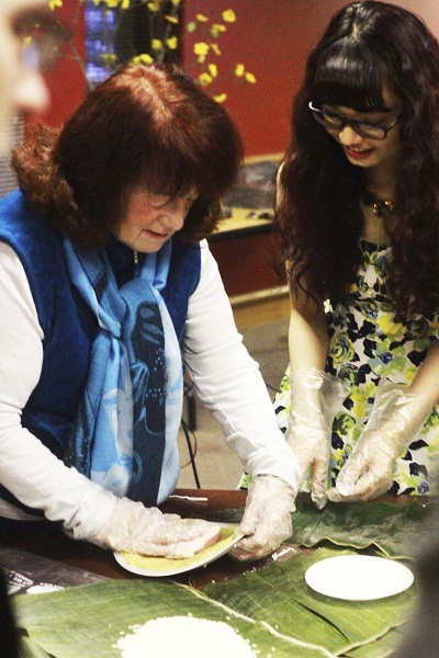 Bác gái người Mỹ cùng một bạn du
học sinh thử gói bánh chưng