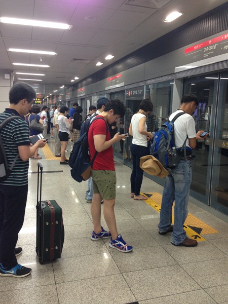 Văn hóa “mì ăn liền” lên ngôi ở Hàn Quốc - 1 Trong lúc chờ tàu, các hành khách đều tranh thủ giải trí bằng điện thoại di động