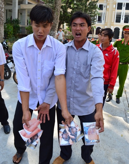 Người nhà bị hại đưa những hình ảnh chứng minh bị gây thương tích phản ứng với phán quyết của tòa.