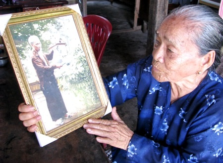 Bà Nguyễn Thị Bảy (con dâu má Tư) nâng niu bức ảnh Bác Hồ tưới cây vú sữa. 