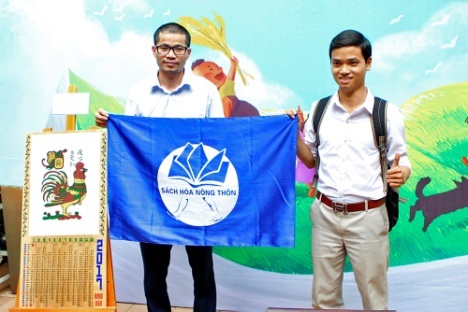 Lịch khuyến đọc đồng hành cùng "sách hóa nông thôn" - 3 Anh Nguyễn Quang Thạch (trái), người đã 19 năm thực hiện “cách mạng thư viện” ở nông thôn Việt Nam giơ cao lá cờ biểu trưng của dự án.