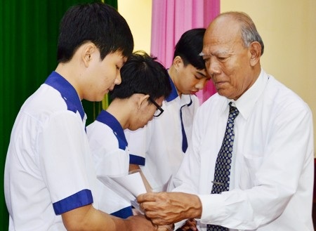 Thầy Lâm Es đang trao học bổng cho học sinh.