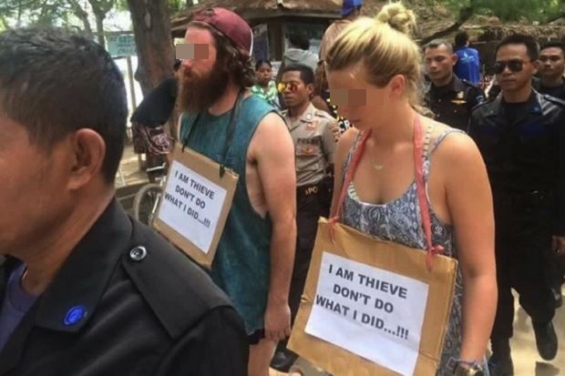 Du khách phải đeo biển "tôi là kẻ trộm" trên đường phố Indonesia - 1 Hai vị khách du lịch bị áp giải với tấm biển mang nội dung “Tôi là kẻ trộm/ Đừng hành động như tôi”
