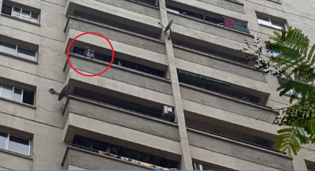 Cháu bé ngồi vắt vẻo trên ban công tầng 12 (Ảnh cắt từ clip của anh Nguyễn Hà).