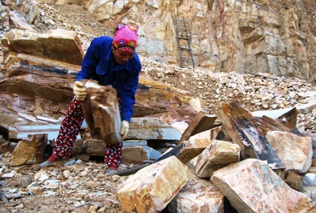 Chị Nguyễn Thị Lài khuân phiến đá nặng vài chục kg để xếp thành đống.