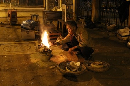 Một cụ ông nhóm lửa nấu xôi bán cho học sinh.