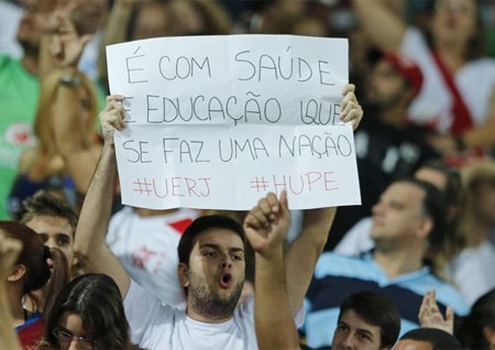 Tấm biểu ngữ với dòng chữ “Y tế và giáo dục làm nên một đất nước” được một CĐV giơ cao tại Maracana