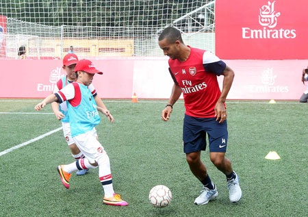 Walcott tranh bóng với một cầu thủ nhí, ảnh: Minh Phương