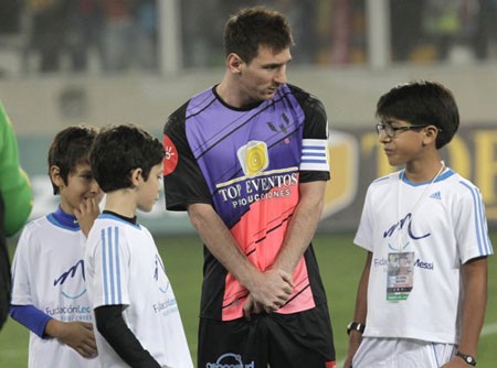 Messi trông khá bẽn lẽn bên cạnh các em nhỏ