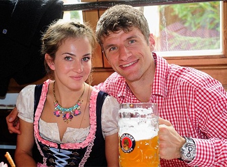 Thomas Muller nâng cốc chúc mừng bằng một vại bia lớn, anh đi cùng vợ Lisa