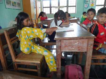 Cô bé dùng chân mở vở như các bạn bình thường khác...