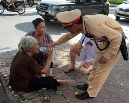 CSGT Hà Nội cứu sống bà cụ hơn 80 tuổi bị say nắng - 1 Thượng úy Sơn đang cho bà cụ uống nước