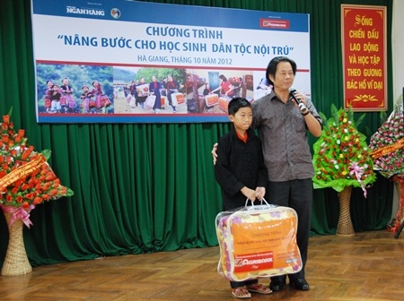 Ông Hoàng Văn Minh - Phó Tổng Biên tập Thời báo Ngân hàng trao tấm chăn ấm tới em Nguyễn Hữu Phúc.