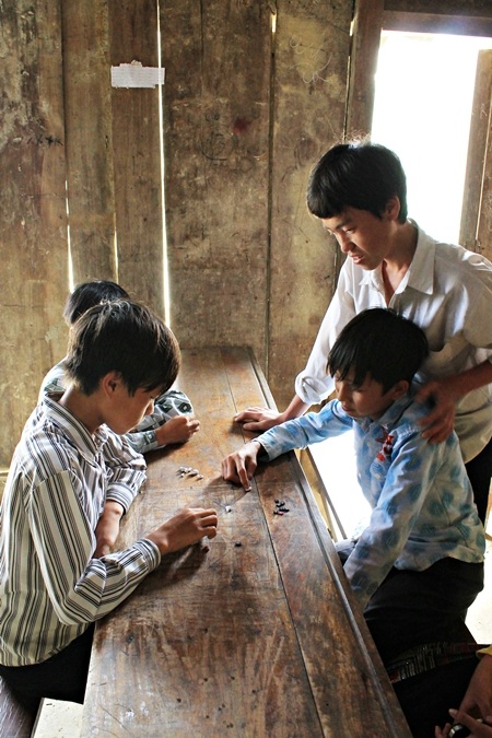 Bàn cờ gánh được vẽ trên bàn học, những viên sỏi được dùng làm quân cờ.