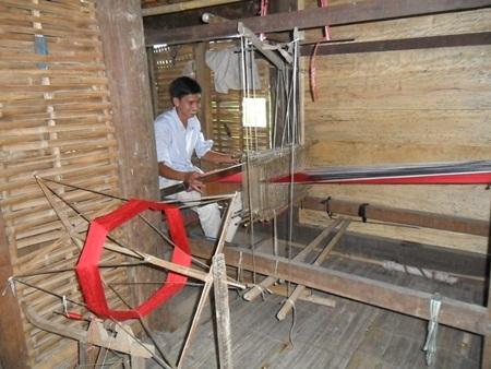 Du khách bên khung cửi dệt vải thổ cẩm.