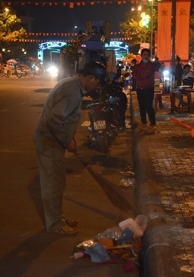 Người lao công lặng lẽ dọn rác trước thời khắc bắn pháo hoa.