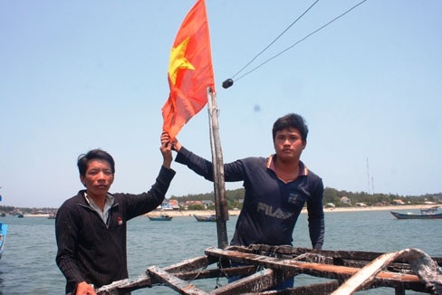 Trao tặng huy hiệu Tuổi trẻ dũng cảm cho hai ngư dân - 1 Anh Thạnh và anh Phải bên lá cờ Tổ quốc (Ảnh: Tiền Phong)
