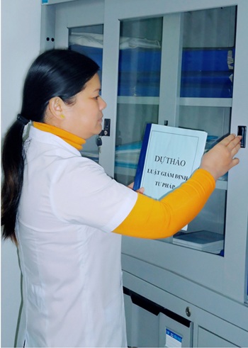 Chị Đoàn Thị Thẩm bên tủ hồ sơ pháp y tại Trung tâm Pháp y Cao Bằng