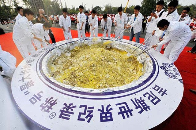 10 kỷ lục thế giới "lãng xẹt" ở Trung Quốc năm 2015 - 1 Khoảng 300 người đã được huy động để chế biến lượng cơm rang nặng nhất thế giới (hơn 4 tấn) tại thành phố Dương Châu. Tổ chức kỷ lục thế giới Guinness ban đầu đã công nhận danh hiệu này nhưng sau đó đã thu hồi vì hạt cơm được cho là vẫn sống sau 4 giờ chế biến.