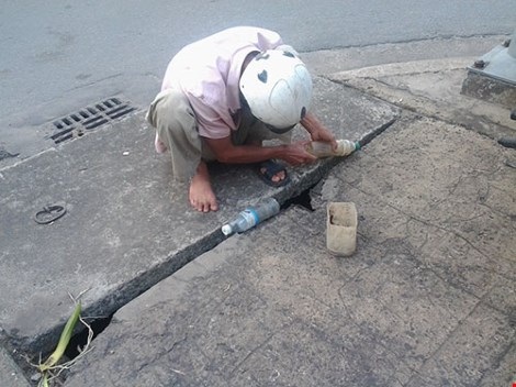  “Thợ câu” Nguyễn Quốc Minh đang “tác nghiệp” qua khe hở của miệng ống cống thoát nước trên đường CMT8 (phường Quyết Thắng, TP.Biên Hòa).