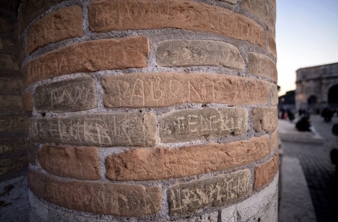 Khách du lịch tự do khắc chữ lên cột đá ở Đấu trường La Mã cổ tại Rome.