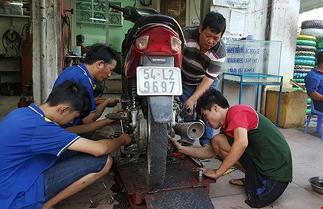 Tiệm sửa xe kỳ lạ giữa Sài Gòn - 1 Anh Phúc (áo thun sọc ngang) cùng các thợ sửa xe của tiệm. Ảnh: HỒNG MINH