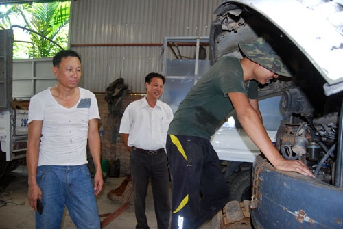 Hải Dương: Phất lên nhờ rủ nhau học nghề... đồng nát - 1 Anh Vũ Phương Hùng (phải) đang được “tiền bối” Vũ Văn Đoàn (ngoài cùng bên trái) hướng dẫn sửa một chiếc xe cũ tại xưởng. Ảnh: M.L