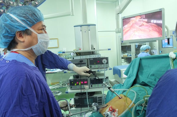 Tự chủ tài chính: Bệnh viện lo nợ, bệnh nhân lo bị “tận thu” - 2 GS Trần Bình Giang (BV Việt Đức) phẫu thuật nội soi một ca ung thư dạ dày tại phòng mổ hiện đại nhất Việt Nam. Ảnh: Diệu Linh