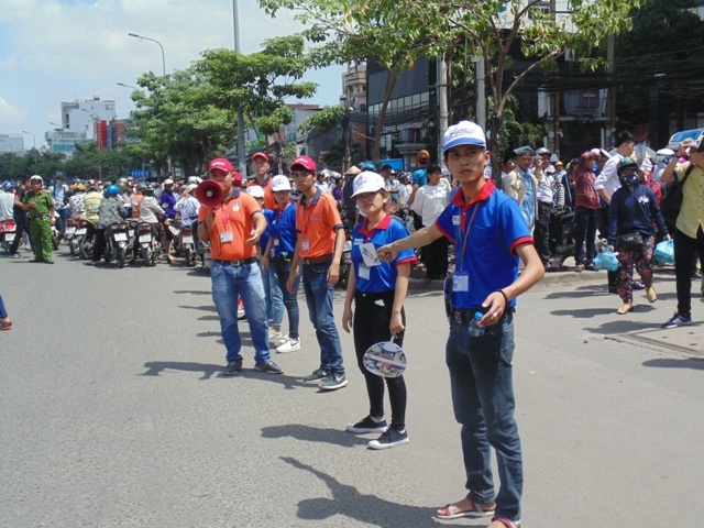 
Dưới cái nắng gắt, các tình nguyện viên vẫn nắm tay nhau thành những dải phân cách nhằm đảm bảo giao thông đi lại. (Ảnh: Xuân Duy)
