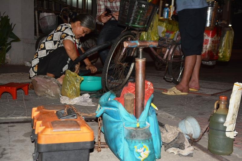 Ở những tiệm sửa xe khác, họ bơm vá bằng máy, còn với bà, hai chiếc bơm sắt bằng tay cùng chiếc hộp nhựa đựng cờ lê, mỏ lết, miếng vá đã theo bà hàng chục năm nay. Bà cũng mua một bịch xăng để bán kiếm thêm vài ba đồng