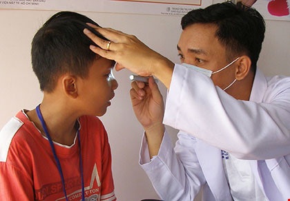 BS chuyên khoa đang khám tật khúc xạ mắt cho học sinh. Ảnh: TRẦN NGỌC