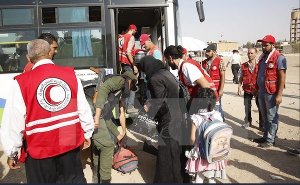Quân đội Syria giành lại quyền kiểm soát thị trấn Daraya - 1 Nhân viên Hội Trăng lưỡi liềm Đỏ Syria hỗ trợ người dân sơ tán khỏi Daraya tới trại tị nạn Herjelleh ở gần Damascus. (Nguồn: EPA/TTXVN)