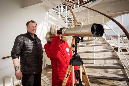 Conrad Field, một nhà sinh vật học đến từ Homer, Alaska bên cạnh một hành khách đang ngắm thiên nhiên từ trên boong tàu với ống nhòm cỡ lớn