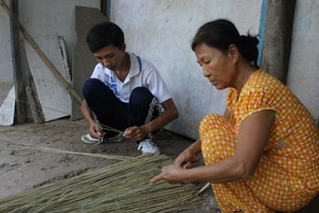 
Sau giờ học, Trí phụ chuốt cọng dừa với mẹ để kiếm tiền mua gạo và lo thuốc thang cho cha
