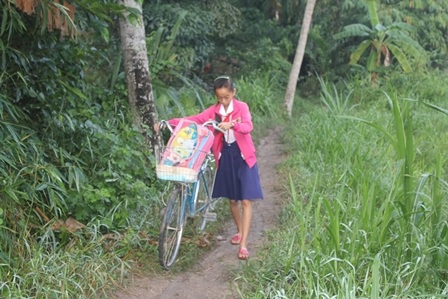 Cháu Sương dẫn bộ chiếc xe đạp từ trong xóm ra đường lớn để đến trường dự lễ khai giảng.