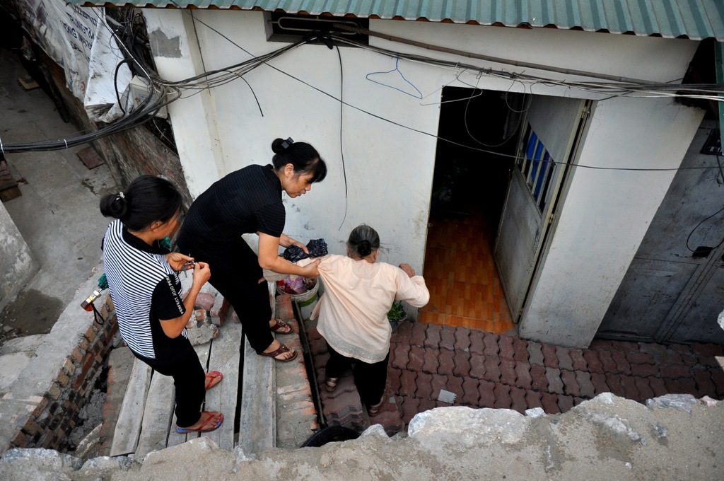 
Mái nhà hai bên đường gần như ngang mặt đường. Để tạo lối di vào nhà, nhiều người dân đành phải bắc thang, xây bậc. Cuộc sống bị xáo trộn.
