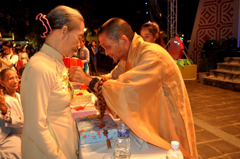 Sư thầy cài hoa hồng cho một trong những người mẹ được tri ân trong đêm hội