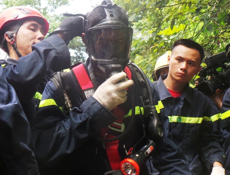 
Chiến sĩ Cảnh sát PCCC đeo mặt nạ phòng độc và bình oxy để xuống hang
