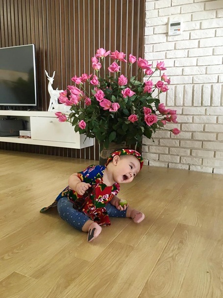 Nhóc tì 10 tháng tuổi nhà Trang Nhung điệu đà áo dài, nón lá - 3 Cô bé cứ “à” một cái là nghiêng đầu một lần, ai gặp cũng muốn cưng nựng. Vani đặc biệt thích hoa tươi. Thấy hoa tươi là cô bé sà xuống, không muốn rời ra.