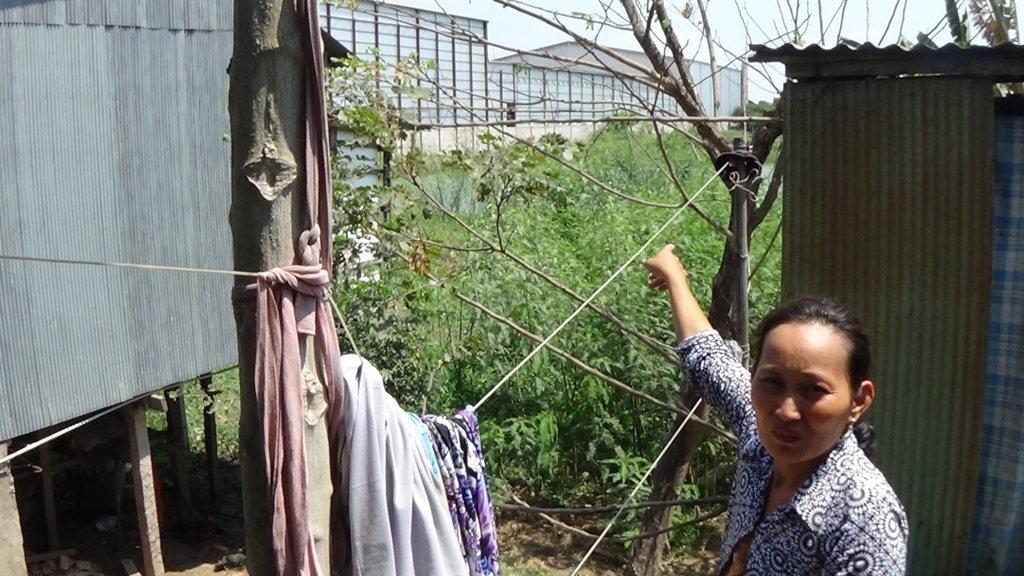 Vợ ông Hào chỉ tay về vách lò sấy và xay xát bị khoét lỗ khiến bụi bay vào dân của ông Đông